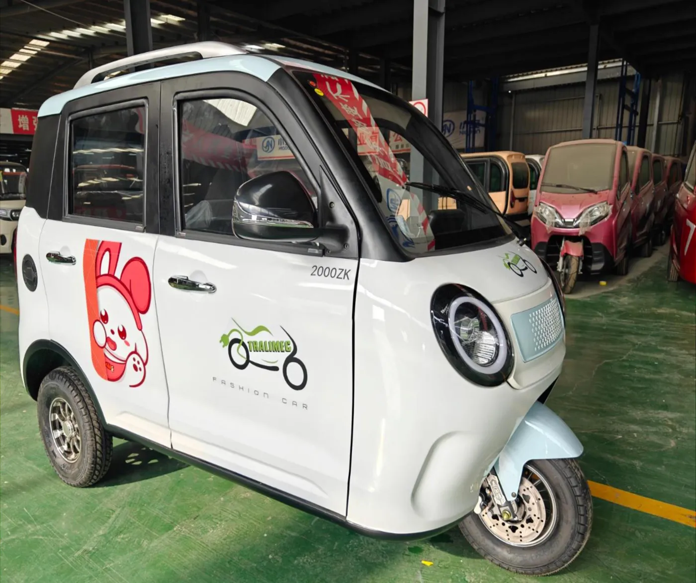 Vehículo eléctrico cabinado blanco con el logo de TRALIMEC